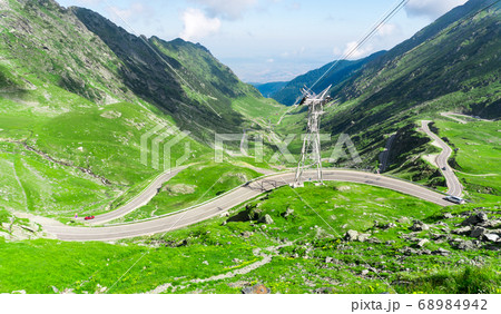 Top vew of winding road in mountains, with red car 68984942