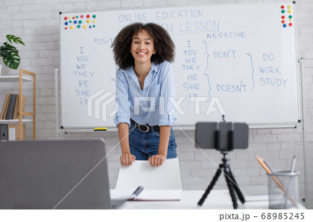 Questions to english teacher online. African american girl near blackboard and looking at webcam 68985245