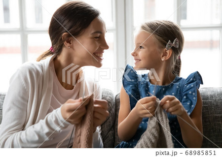 Young biracial woman teaching little child daughter knitting. 68985851
