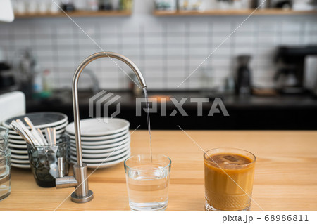 water is pouring from a tap into a glass 68986811