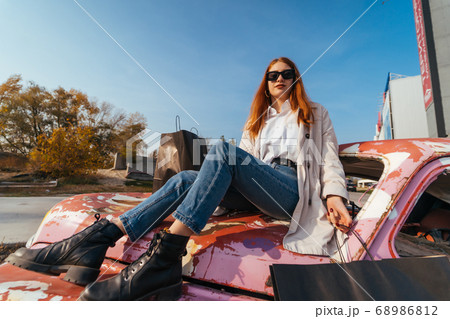 Young woman sits on an old decorated car 68986812