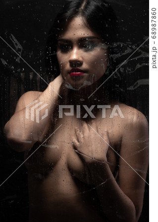 Perfect shape of woman body. Sexy art nude female. Naked sensual beautiful girl. Asian erotic light shadow and silhouette green leaf on breast over dark smoke background copy space 68987860