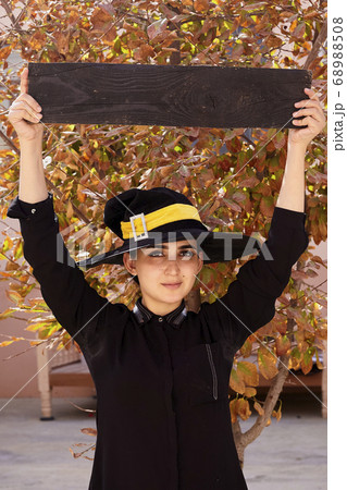 Woman in witch hat holding a wooden desk Woman in witch hat holding a wooden desk 68988508
