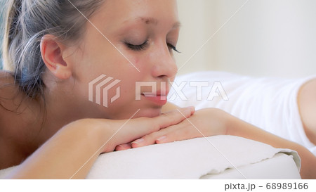 Relaxed young woman lying on spa bed for massage. Relaxed young woman lying on spa bed for massage. 68989166