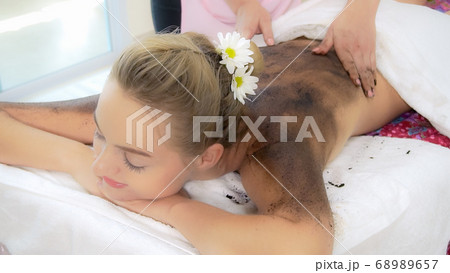 Relaxed woman lying on spa bed for body scrubbing. 68989657