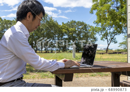 公園でリモートワークするビジネスマン 公園でリモートワークするビジネスマン 68990873