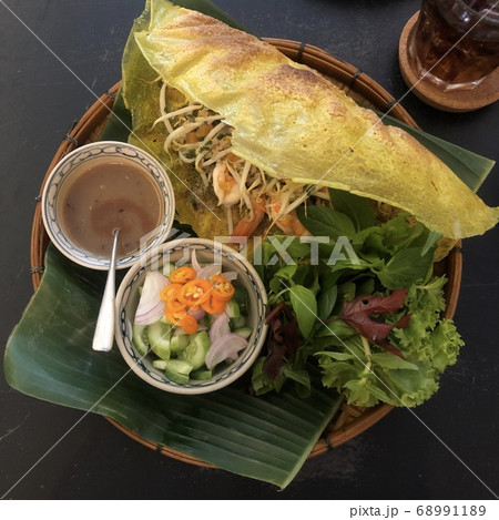 Banh Xeo. Sizzling crispy thin yellow pancake. Vietnamese food. Top-down composition. Dark table. 68991189