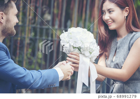 Caucasian handsome man giving flowers to asian 68991279