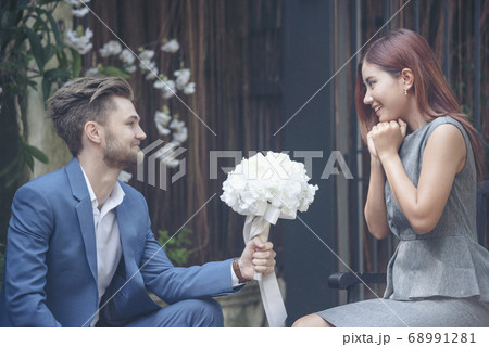 Caucasian handsome man giving flowers to asian 68991281