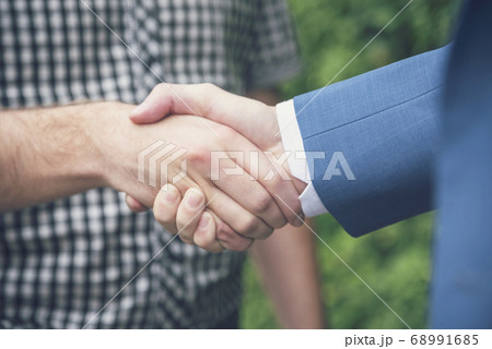 Business Partners shaking hands together in green 68991685
