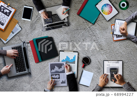 Top view of businessman Group of Multiethnic Busy People meeting with other in modern office with laptop computer, smartphone, tablet, coffee and document on table. 68994227