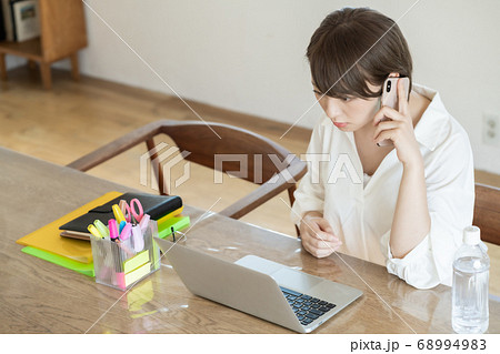 テレワーク中携帯電話で話す若い女性 テレワーク中携帯電話で話す若い女性 68994983