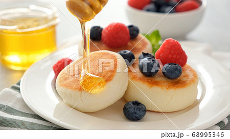 Cottage cheese fritters with honey and berries 68995346