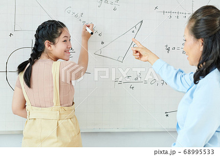 Schoolgirl writing equation on whiteboard Schoolgirl writing equation on whiteboard 68995533