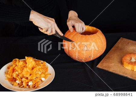 Jack's Halloween pumpkin. Girl's hand with a knife cutting an orange pumpkin 68998641