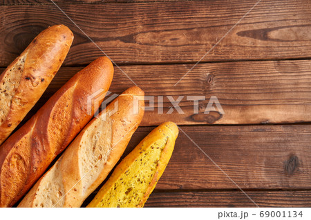 Three crispy french baguettes lie on an old wooden 69001134
