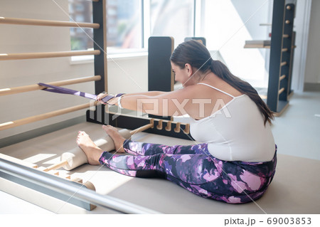 Woman trying to stretch her muscles with special equipment Woman trying to stretch her muscles with special equipment 69003853