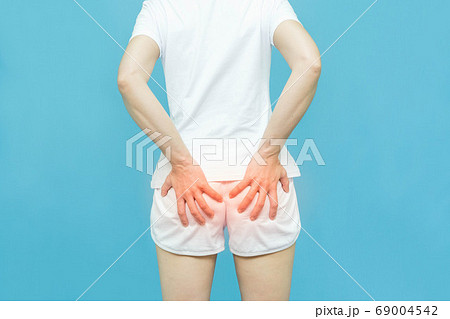 woman in white clothes put her hand on the bottom area, painful illness feeling unwell ,Hemorrhoids concept on white background 69004542