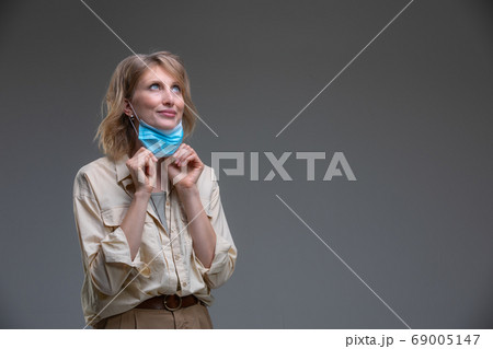 Blond woman take off her surgical mask 69005147