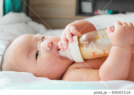 Portrait of a newborn Asian baby on the bed drinks Portrait of a newborn Asian baby on the bed drinks 69005516
