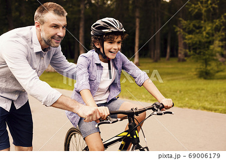 Boy learning to ride bicycle with his dad Boy learning to ride bicycle with his dad 69006179