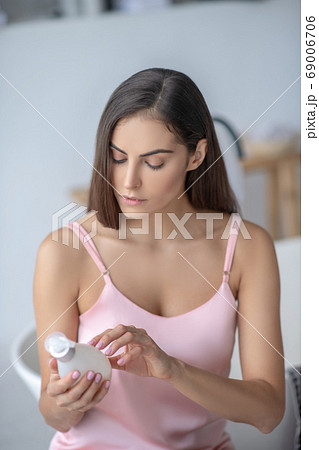 Pretty long-haired woman reading about new body lotion 69006706