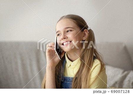 Girl talking on cell phone sitting on couch Girl talking on cell phone sitting on couch 69007128