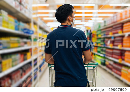 One young man pushing trolley in supermarket One young man pushing trolley in supermarket 69007699
