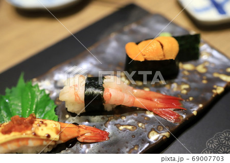 Shrimp sushi on a traditional Japanese plate in a Japanese restaurant. Selective focus. Shrimp sushi on a traditional Japanese plate in a Japanese restaurant. Selective focus. 69007703