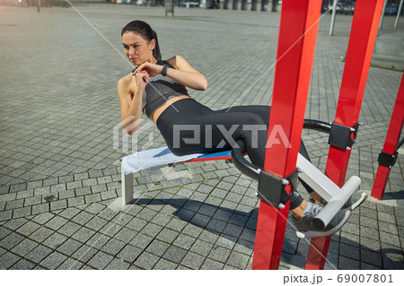 Active female person doing morning exercises outdoors 69007801