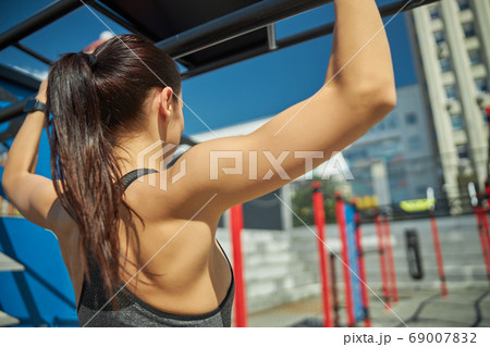 Serious longhaired brunette looking at sport equipment 69007832