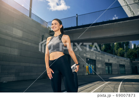 Charming active brunette girl stretching her leg Charming active brunette girl stretching her leg 69007873