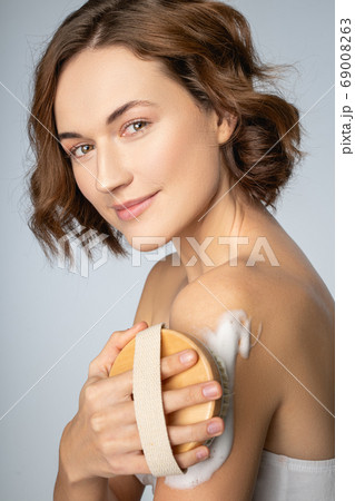 Beautiful dark-haired woman performing an exfoliation procedure 69008263