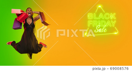 Portrait of young woman in neon light on gradient backgound. The human emotions, black friday, cyber monday, purchases, sales, finance concept. Neoned lettering. Portrait of young woman in neon light on gradient backgound. The human emotions, black friday, cyber monday, purchases, sales, finance concept. Neoned lettering. 69008576