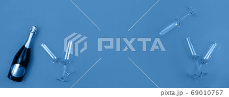 Champagne bottle and glasses on trendy blue background with place for text. Holiday concept. Mockup for your web banner design. Flat lay style. 69010767