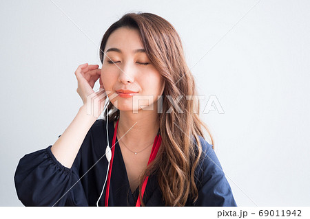 イヤホンの音に耳を傾ける女性 イヤホンの音に耳を傾ける女性 69011942