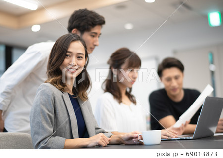 データを確認しながらパソコン操作する女性社員とその側でアドバイスと談笑をする男性上司達 データを確認しながらパソコン操作する女性社員とその側でアドバイスと談笑をする男性上司達 69013873