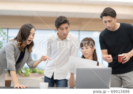 データを確認しながらパソコン操作する女性社員とその側でアドバイスと談笑をする男性上司達 データを確認しながらパソコン操作する女性社員とその側でアドバイスと談笑をする男性上司達 69013896