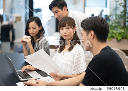 データを確認しながらパソコン操作する女性社員とその側でアドバイスと談笑をする男性上司達 データを確認しながらパソコン操作する女性社員とその側でアドバイスと談笑をする男性上司達 69013908