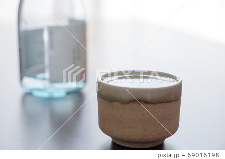 お猪口になみなみと注いだ酒と瓶 69016198