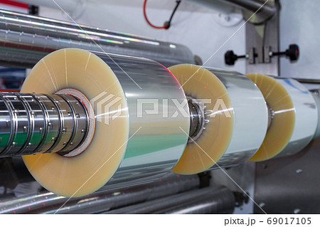 plastic packaging film on automatic packing machine in food product factory. industrial concept. . plastic packaging film on automatic packing machine in food product factory. industrial concept. . 69017105
