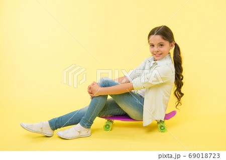 Girl ride penny board yellow background. Kid 69018723