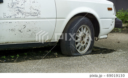 Old worn out and rusted abandoned car with flat 69019130