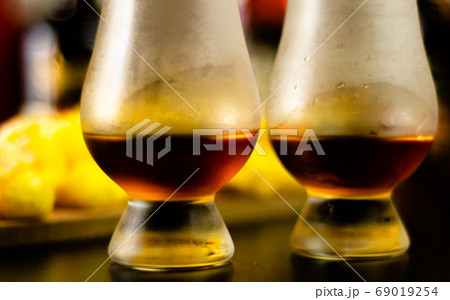 glass of whiskey with ice cubes and salty snacks 69019254