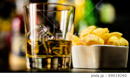 glass of whiskey with ice cubes and salty snacks glass of whiskey with ice cubes and salty snacks 69019260