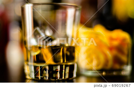 glass of whiskey with ice cubes and salty snacks glass of whiskey with ice cubes and salty snacks 69019267