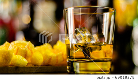 glass of whiskey with ice cubes and salty snacks glass of whiskey with ice cubes and salty snacks 69019279