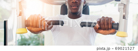 African American athlete doing exercise for chest muscles on pec deck machine during workout in gym African American athlete doing exercise for chest muscles on pec deck machine during workout in gym 69021527