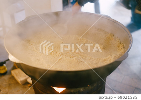 Raw rice was poured into a huge cauldron with pilaf. Raw rice was poured into a huge cauldron with pilaf. 69021535