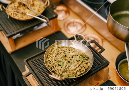 A close-up of a frying pan with spaghetti on a cast iron stove in the kitchen during cooking. 69021806